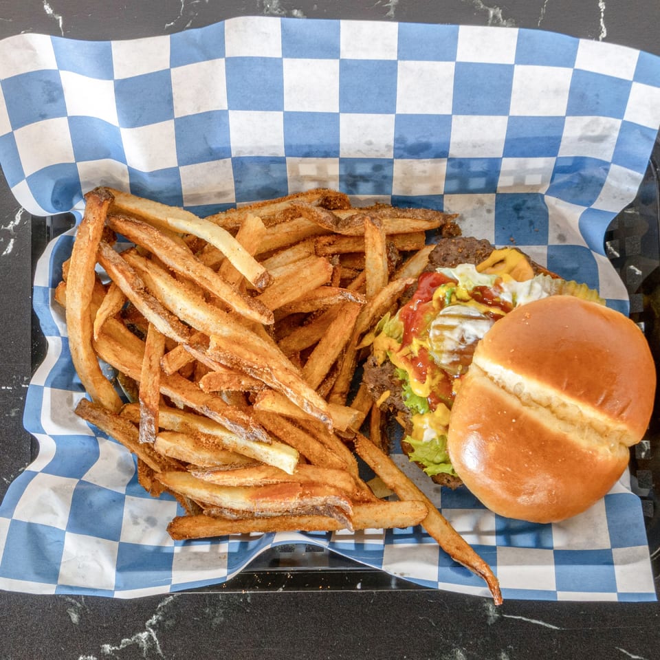 A Suthern Cluck burger with lettuce, tomato, and sauce, served with a side of fries.
